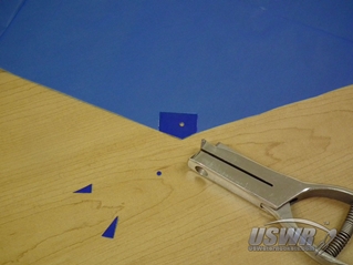 Use a hole punching tool to make a hole in each corner of the paracute.