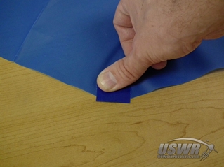 Fold the duct tape to cover both sides of the parachute material.